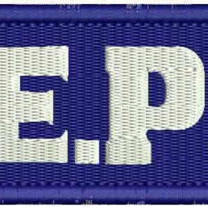 Könnte beinhalten: Weiße gestickte Buchstaben, die "N.E.P.S." auf einem blauen rechteckigen Patch buchstabieren.