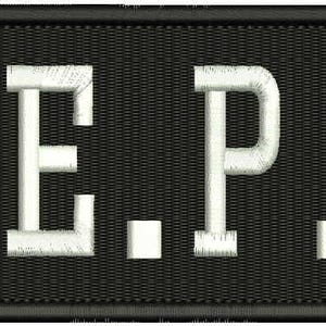 Puede incluir: Parche negro bordado con las letras blancas "N.E.P.S.". Las letras son en bloque y texturizadas, con pequeños cuadrados blancos entre ellas. El parche es rectangular con un borde negro.