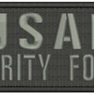 Könnte beinhalten: Ein schwarzer Patch mit dem Text "USAF SECURITY FORCES" in Weiß.