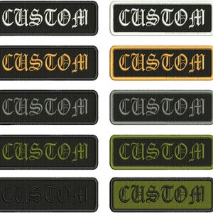 Puede incluir: Diez parches rectangulares bordados dispuestos en dos columnas, cada uno con la palabra CUSTOM en una fuente gótica. Los parches varían en colores de fondo e hilo, incluyendo combinaciones de negro, blanco, oro, gris, verde oliva y verde oscuro.