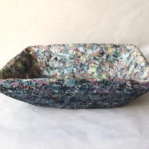 May include: A set of three ceramic nesting bowls in shades of blue, green, and white. The bowls feature a speckled glaze and a simple, modern design. The largest bowl measures approximately 6 inches in diameter.