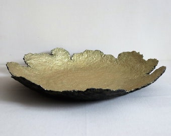 A large paper mache plate of irregular shape with a golden top and a dark bottom. Recycled papier art. Unique plate for centerpieces.
