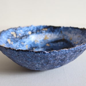 Ciotola in cartapesta blu con macchie d'oro. Piatto decorativo in carta riciclata. Cattura unico tutto il piatto.