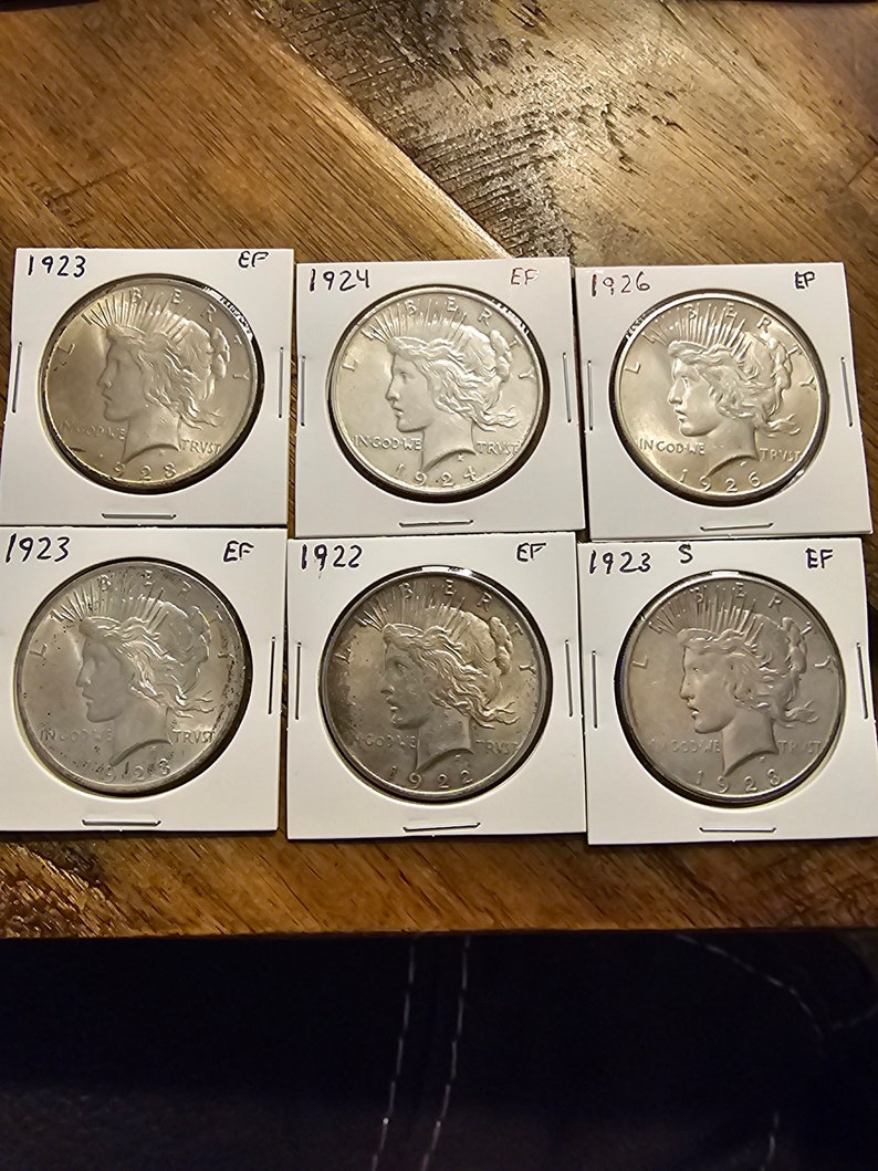 May include: Six silver Peace Dollar coins from 1922, 1923, 1924, 1926, and two from 1923, all in excellent condition.