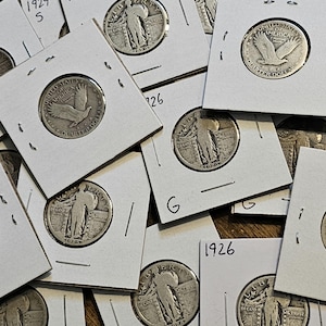 May include: A collection of silver Walking Liberty half dollar coins from 1926 and 1929, displayed on white card stock with the year printed on each card.