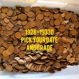 May include: A large container filled with copper-colored US pennies. The pennies are dated 1928-1933D. The text "Pick Your Date and Grade" is written in yellow letters on a black background.