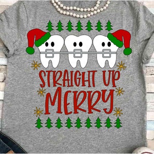 May include: Gray t-shirt with a Christmas-themed design. The design features three cartoon teeth wearing braces and Santa hats, with the text "STRAIGHT UP MERRY" in red. Green Christmas trees and yellow stars complete the design.