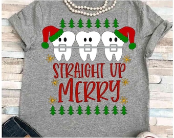 May include: Gray t-shirt with a Christmas-themed design. The design features three cartoon teeth wearing braces and Santa hats, with the text "STRAIGHT UP MERRY" in red. Green Christmas trees and yellow stars complete the design.