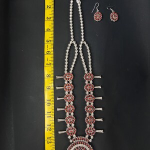 May include: A silver necklace with a horseshoe pendant and red coral beads. The necklace is 15 inches long and has a matching pair of earrings.