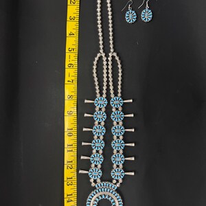 May include: A turquoise and silver Native American necklace with a horseshoe pendant and matching earrings. The necklace is approximately 15 inches long.