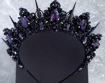 May include: A black crown with purple gemstones and sharp points. The crown is made of metal and has a headband.