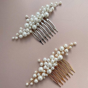 May include: Two hair combs with pearl accents. One comb has a silver finish, and the other has a gold finish. Both combs feature clusters of white pearls attached to the comb's teeth.