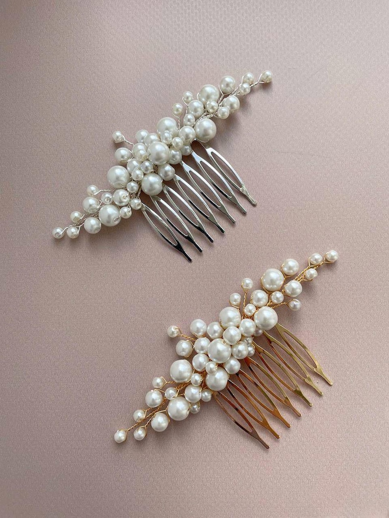 May include: Two hair combs with pearl accents. One comb has a silver finish, and the other has a gold finish. Both combs feature clusters of white pearls attached to the comb's teeth.