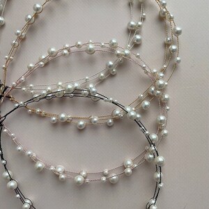 May include: Four strands of pearl jewelry with different colored wires. The strands are made of small white pearls and thin wires in gold, silver, pink, and black.