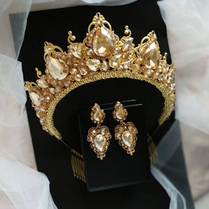 Puede incluir: Una corona dorada con diamantes de imitaci&oacute;n transparentes y &aacute;mbar y pendientes a juego. La corona tiene un peine en la parte posterior para facilitar su colocaci&oacute;n en el cabello.