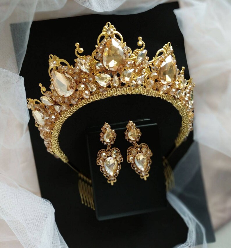 Puede incluir: Una corona dorada con diamantes de imitaci&oacute;n transparentes y &aacute;mbar y pendientes a juego. La corona tiene un peine en la parte posterior para facilitar su colocaci&oacute;n en el cabello.