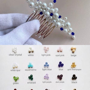May include: A bridal hair comb featuring white faux pearls and blue crystal accents. The comb is made of silver-toned metal and has multiple tines. A color chart with various crystal colors is also shown.
