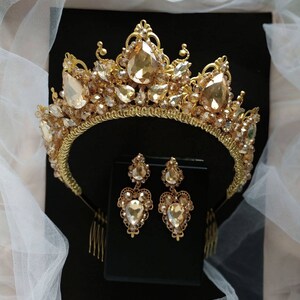Puede incluir: Una tiara dorada con una corona en forma de l&aacute;grima y pendientes a juego. La tiara est&aacute; adornada con diamantes de imitaci&oacute;n transparentes y color champ&aacute;n.