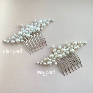 May include: Two bridal hair combs with pearl accents. One comb features white pearls, the other ivory pearls. Each comb has a silver-toned metal base with multiple teeth. The text "white pearl" and "ivory pearl" are written on the image.