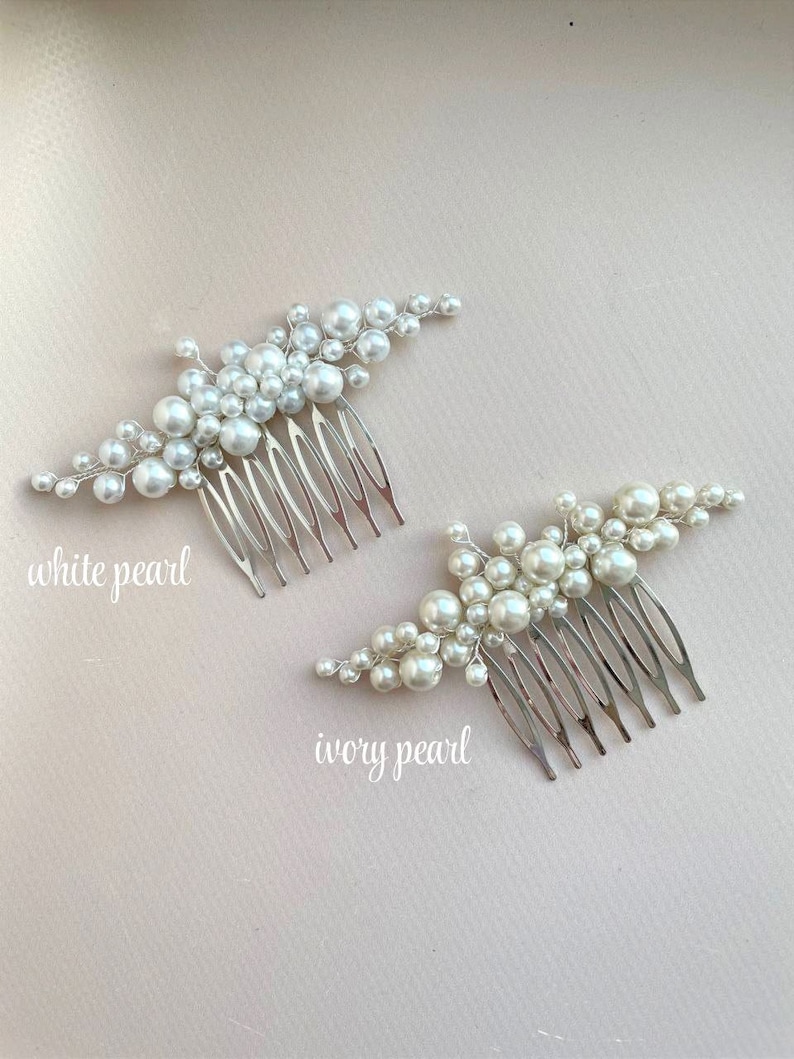 May include: Two bridal hair combs with pearl accents. One comb features white pearls, the other ivory pearls. Each comb has a silver-toned metal base with multiple teeth. The text "white pearl" and "ivory pearl" are written on the image.
