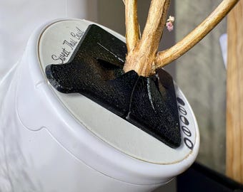 Peut inclure: Un pot de culture hydroponique d'intérieur blanc avec un insert en plastique noir imprimé en 3D retenant une tige de plante. La surface du pot porte l'inscription Sweet Thai Basil et une rangée verticale de cinq icônes circulaires.