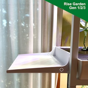 Può includere: Scaffale in metallo bianco con un vassoio in plastica bianca. Lo scaffale è etichettato "Rise Garden Gen 1/2/3".