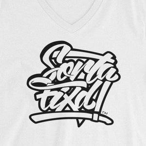 May include: White V-neck t-shirt with a black graphic design that says "Santa Tx" with a trademark symbol.