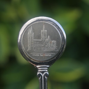 May include: Silver spoon with a round, engraved design featuring a cathedral and the text "TRINITY CATHEDRAL".