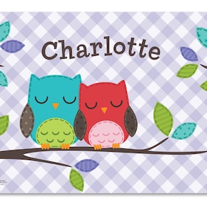 May include: A purple and white checkered background with two owls on a branch. The owls are red and blue with closed eyes. The text "Charlotte" is written in brown letters above the owls.
