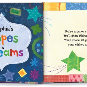 May include: A blue book with a colorful design on the cover. The title of the book is "Sophia's Hopes & Dreams". The text on the right page reads "You're a super star, Sophia. You'll show Michael the ropes. You'll share all your dreams, your wishes and hopes."