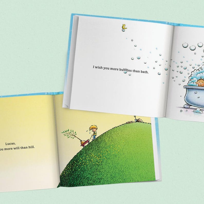 May include: A children's book with illustrations and text. One page reads "I wish you more bubbles than bath." Another page shows a child pushing a tree up a hill. The book has a light blue cover and pages.
