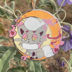 May include: A gray and white cartoon fox with pink accents and a white fluffy tail. The fox is surrounded by a yellow and orange crescent moon with pink and red swirls. The background is a green leafy plant.