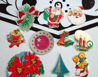 May include: A collection of vintage Christmas paper decorations. The decorations include a Santa Claus, a Christmas tree, a poinsettia, a bell, a candle, and a wreath. The decorations are all in various colors, including red, green, blue, and white.