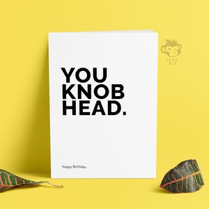 May include: White card with black text that reads "YOU KNOB HEAD."  The text "Happy Birthday..." is at the bottom of the card.