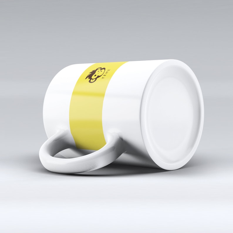 May include: White ceramic mug with a yellow stripe and a brown monkey graphic with the text "TEME" on it.