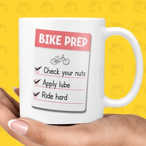 May include: White ceramic mug with a red and white checklist that says "Bike Prep" and includes the following items: "Check your nuts", "Apply lube", and "Ride hard".