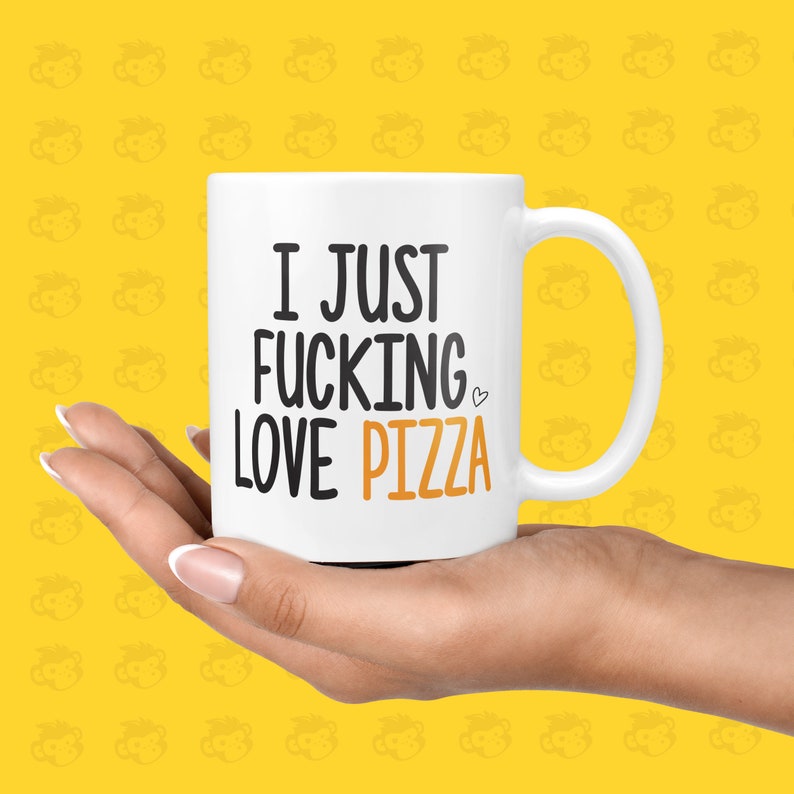 May include: White ceramic coffee mug with a black and orange design. The mug has a handle and says "I JUST FUCKING LOVE PIZZA" with a heart symbol.