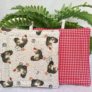 May include: Two pot holders, one with a red and white gingham pattern and the other with a white background and a repeated pattern of brown roosters.