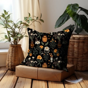 This square throw pillow features a repeating patterns of white daisies and yellow wildflowers in assorted brown and green vases on a black background. Perfect dark academia decor. Printed on both sides of pillow.