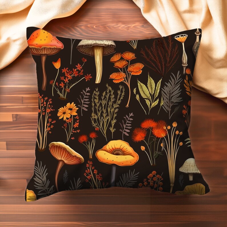 Pillow on a wood table. Pillow has orange and yellow mushrooms, and red, yellow and brown forest flowers all on a black background.