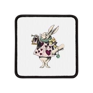 May include: A white rabbit wearing a pink and white vest with a heart pattern, a green and white collar, and a yellow bow tie. The rabbit is holding a scroll in one hand and a trumpet in the other. The rabbit is playing the trumpet.