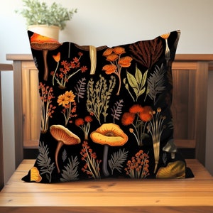 Pillow on a chair. Pillow has orange and yellow mushrooms, and red, yellow and brown forest flowers all on a black background. Printed on both sides