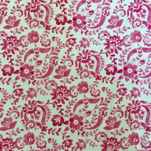 May include: A white fabric with a repeating pattern of pink floral designs. The pattern features stylized flowers and leaves.