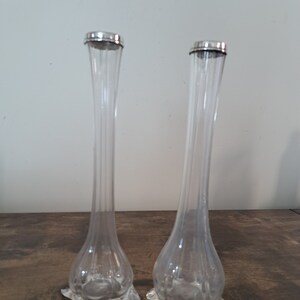 May include: Two clear glass bud vases with silver tops and star-shaped bases.