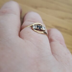 May include: A gold ring with three stones. The center stone is black and the two stones on either side are white.