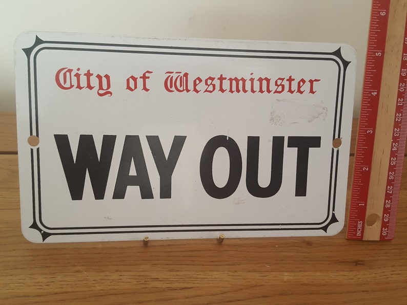 Może przedstawiać: Biały metalowy znak z czarnym napisem "City of Westminster" i "WAY OUT".