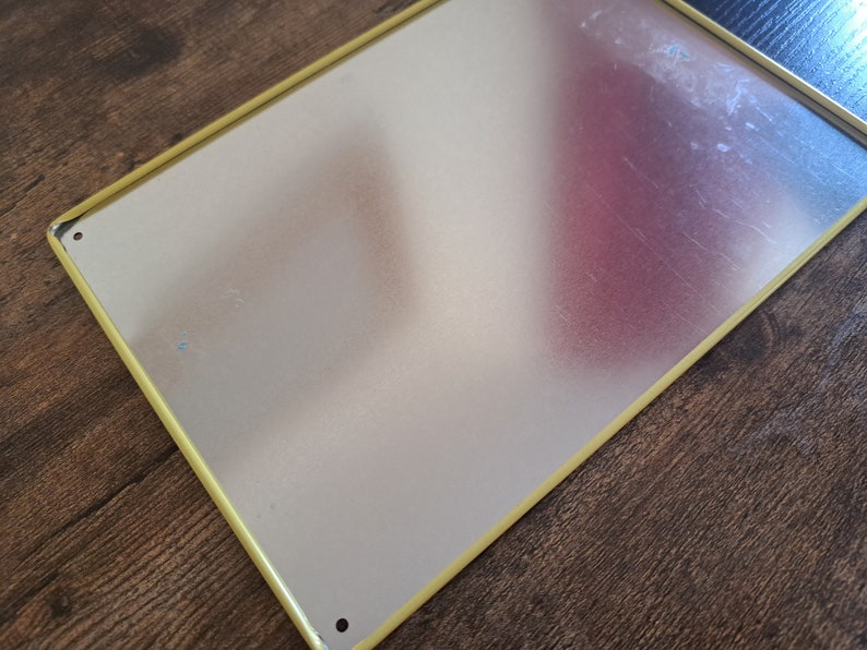 May include: A blank metal sign with a yellow border. The sign is made of a thin metal sheet and has a slightly textured surface.