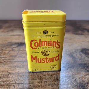 Pode incluir: Uma lata de metal amarela com um rótulo vermelho e preto que diz "Colman's of Norwich Mustard Powder." A lata pesa 57 gramas e tem um logotipo de cabeça de touro.