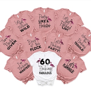 May include: A set of ten pink t-shirts with flamingo graphics and black text. The shirts have various sayings including "Let's get flocking wild", "Zero flocks given", "Boss of this flock", "I'm flocking wasted", "Let's get flocked up", "Party like a flockstar", "Let's flocking party", "Where's the flocking tequila", "60 flocking fabulous", and "Let's flamingle".