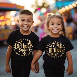 May include: Two children wearing black t-shirts with gold lettering. The shirts say "Birthday Squad" and "7th Birthday Girl". Both shirts have a graphic of a witch's hat and a flying broomstick.